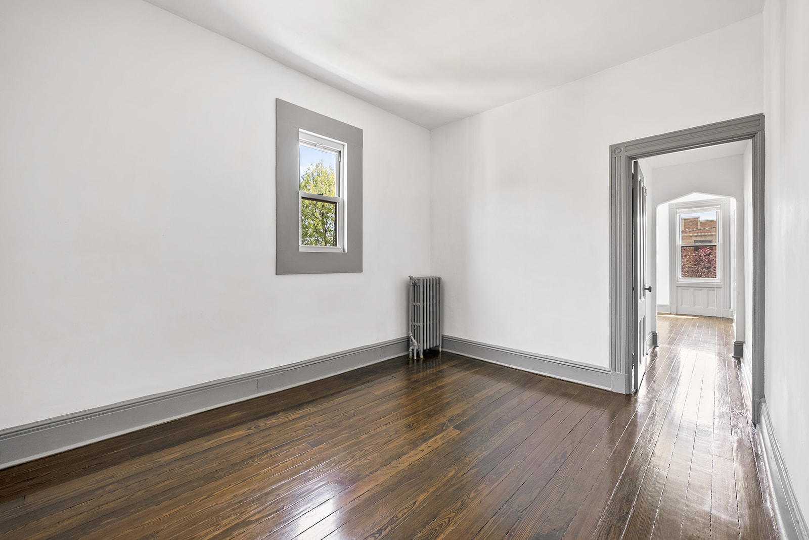59-45 Palmetto Street Queens, NY 11385 - Photo 13 of 25 a view of an empty room with wooden floor and a window