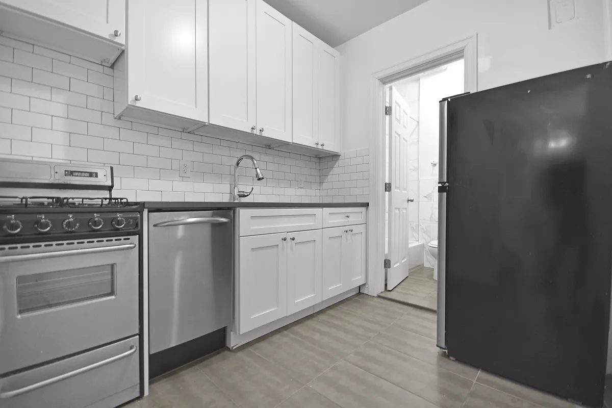 209 East 88th Street, Unit 4B Manhattan, NY 10128 - Photo 4 of 5 a kitchen with white cabinets and white appliances