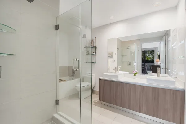 a bathroom with a double vanity sink toilet mirror and shower