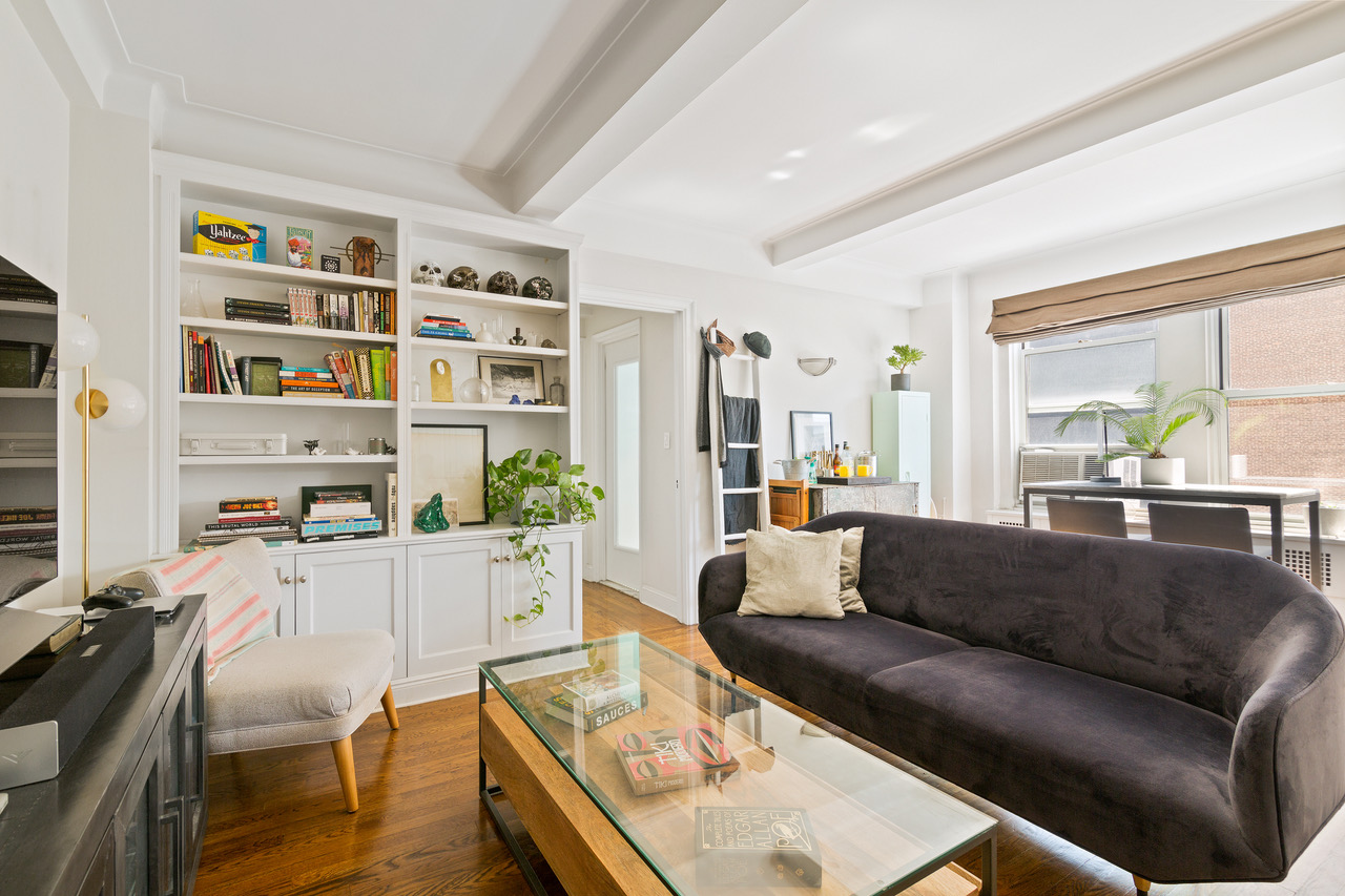 433 West 34th Street, Unit 5J Manhattan, NY 10001 - Photo 2 of 9 a living room with furniture and a book shelf