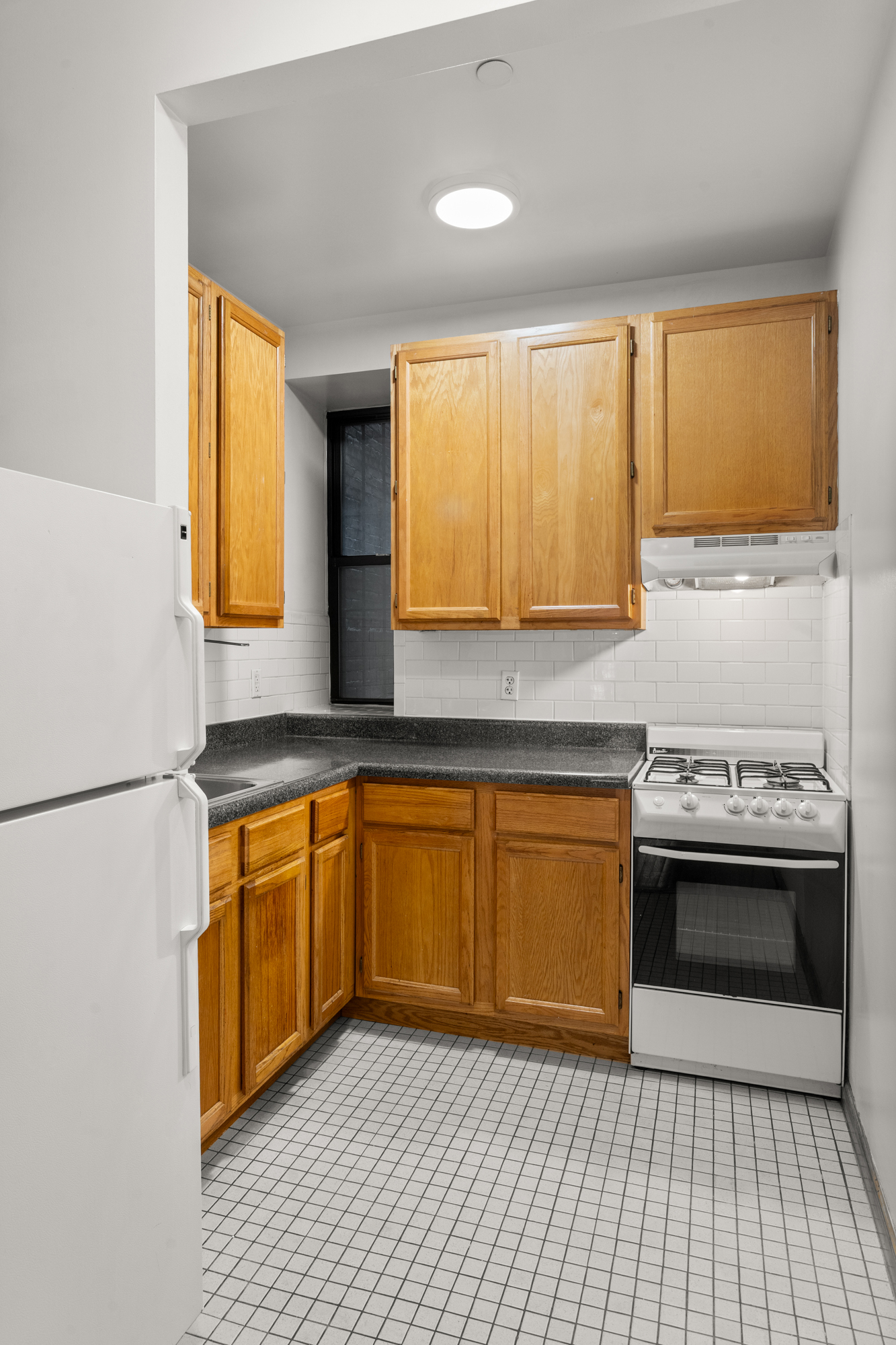 316 West 47th Street, Unit 1FE Manhattan, NY 10036 - Photo 4 of 9 a kitchen with stainless steel appliances granite countertop a sink a stove a refrigerator a washer and dryer