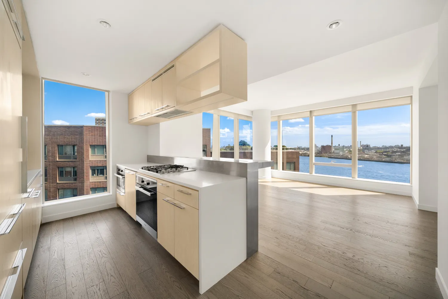 a large kitchen with stainless steel appliances a large window and wooden floor