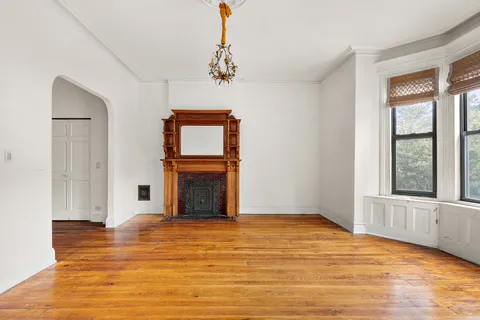 a view of an empty room with a window and wooden floor