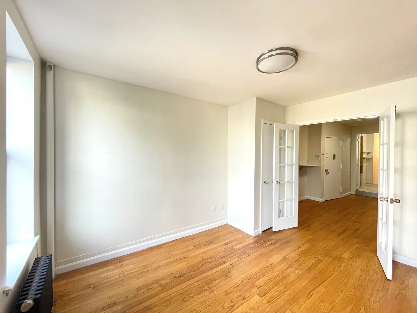 a view of empty room with wooden floor and fan