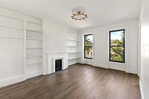a view of an empty room with a window and wooden floor