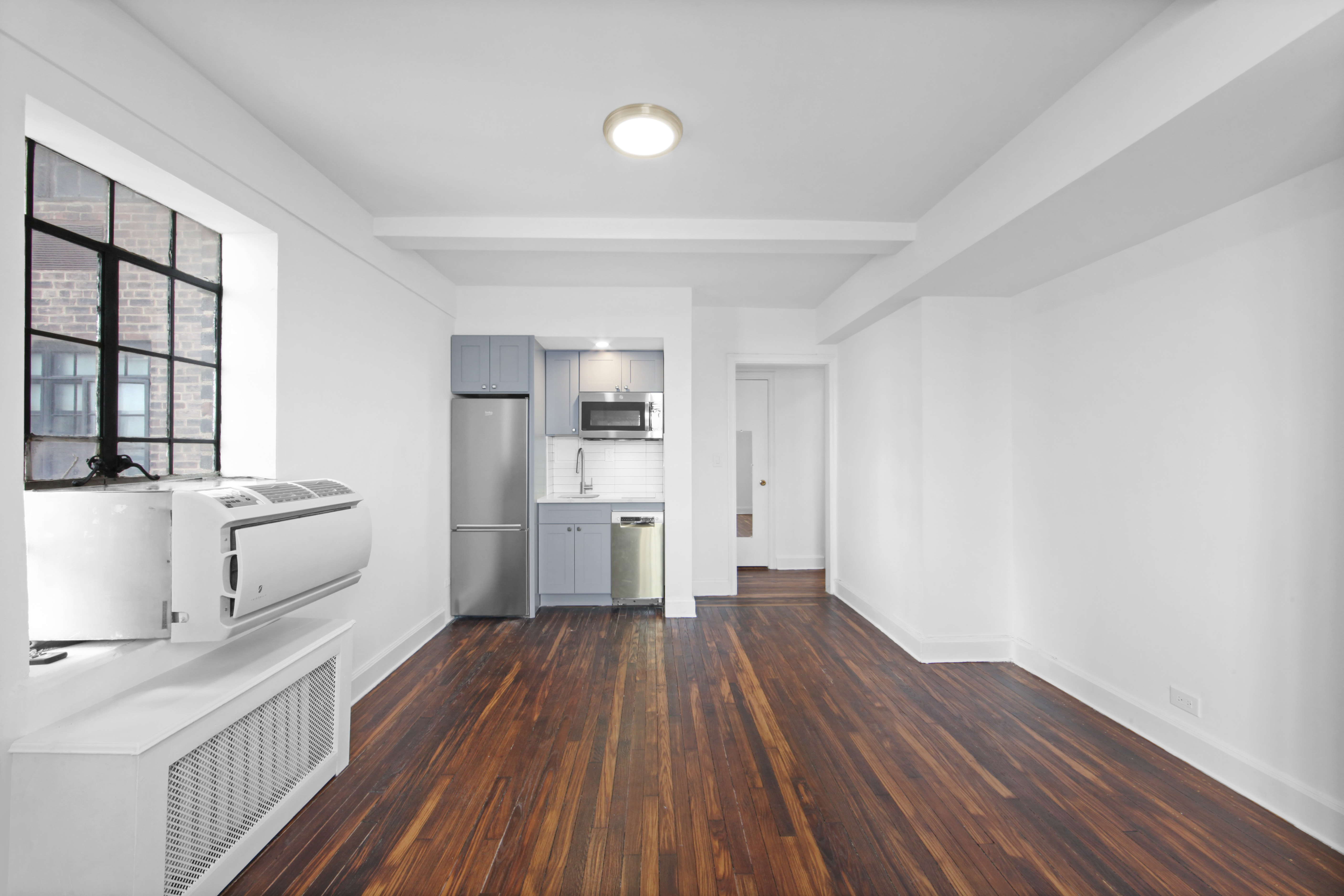 5 Tudor City Place, Unit 1536 Manhattan, NY 10017 - Photo 15 of 21 a kitchen with wooden floors and white appliances