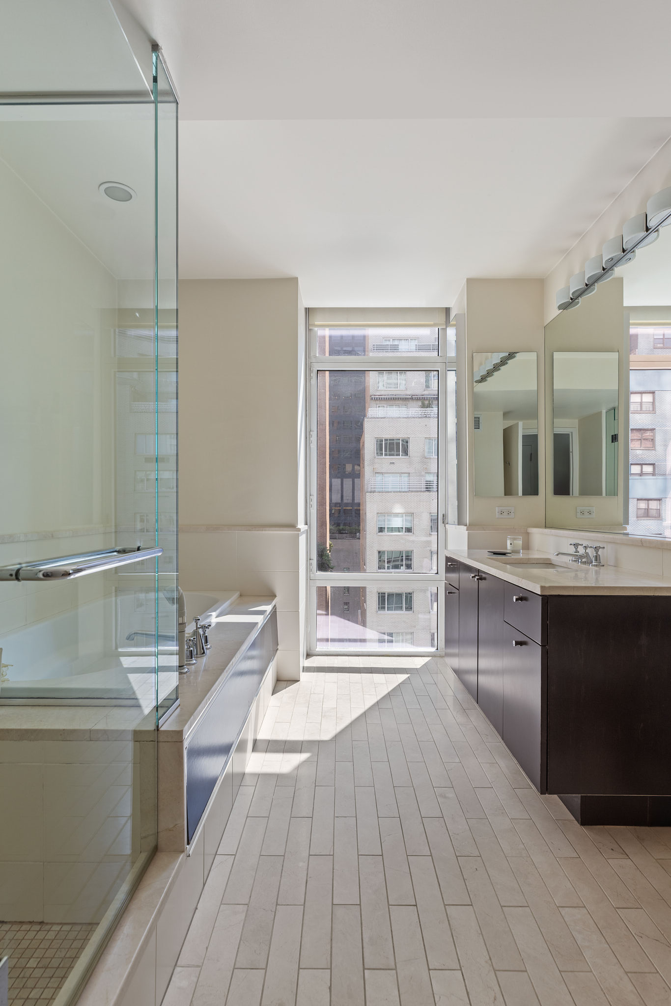 207 East 57th Street, Unit 14B Manhattan, NY 10022 - Photo 5 of 8 a bathroom with a double vanity sink a mirror and a bathtub