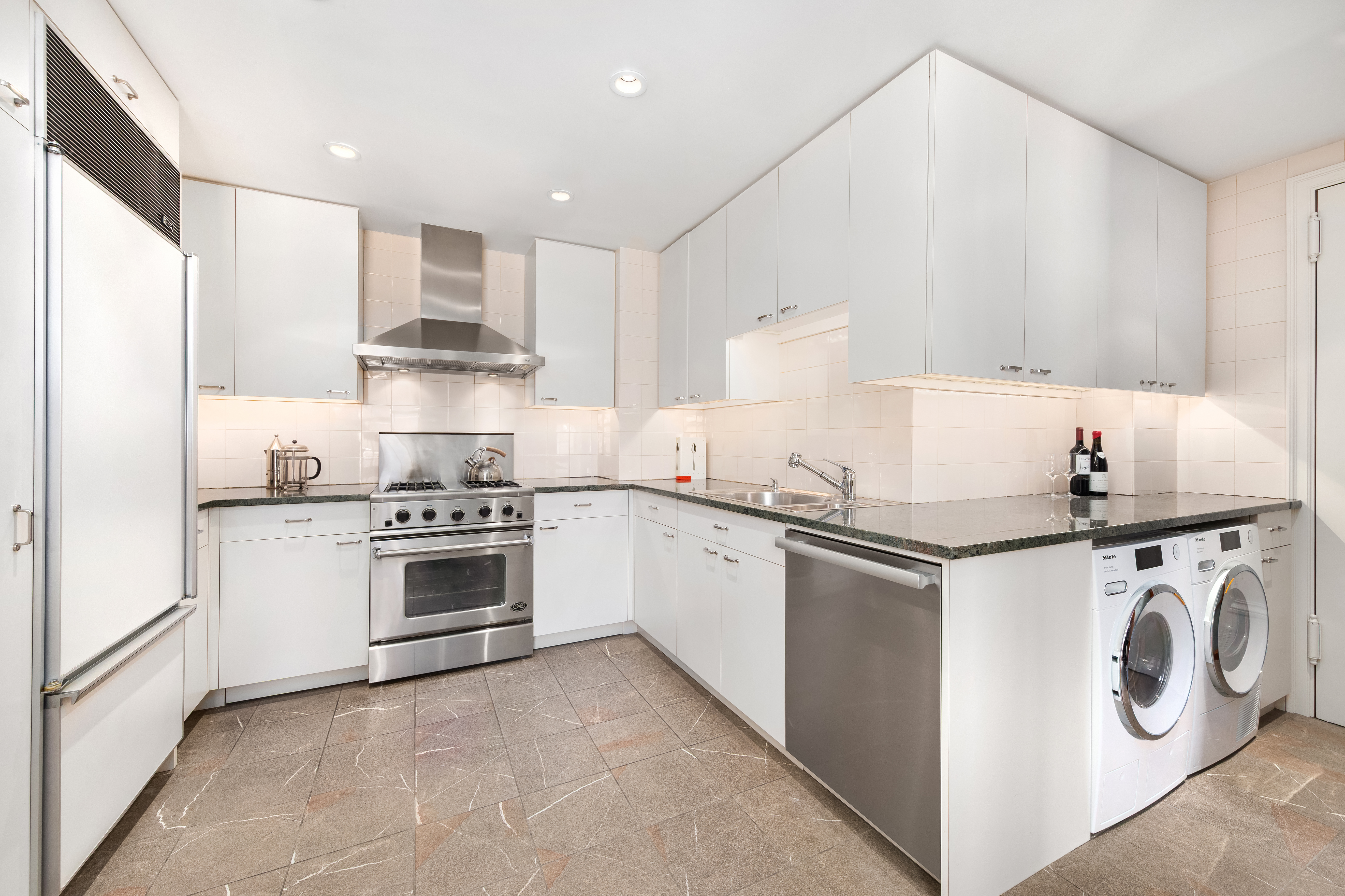 162 East 80th Street Manhattan, NY 10075 - Photo 4 of 13 a kitchen with stainless steel appliances granite countertop a sink a stove a refrigerator and white cabinets