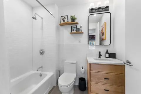 a bathroom with a toilet sink vanity tub and mirror