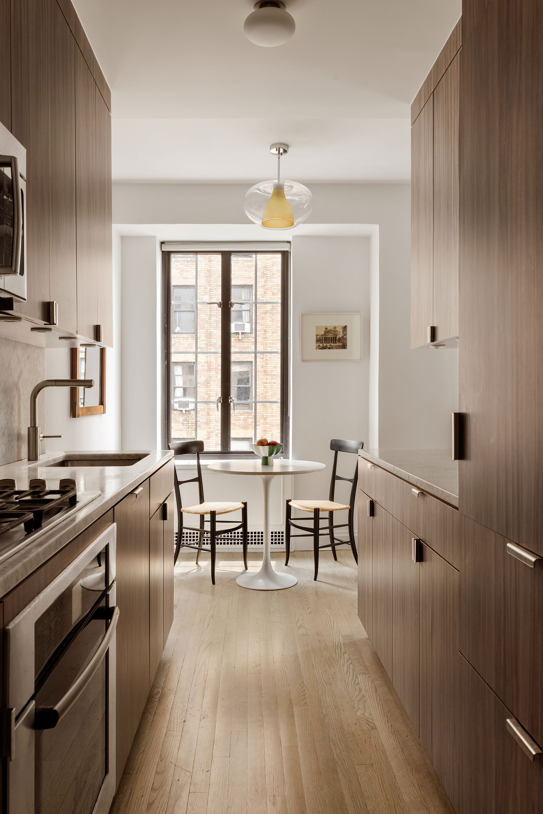 201 West 16th Street, Unit 9A Manhattan, NY 10011 - Photo 5 of 14 a kitchen with stainless steel appliances a stove a sink a dining table and chairs with wooden floor