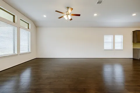 an empty room with wooden floor and windows