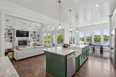 a kitchen with stainless steel appliances a dining table chairs stove refrigerator and cabinets