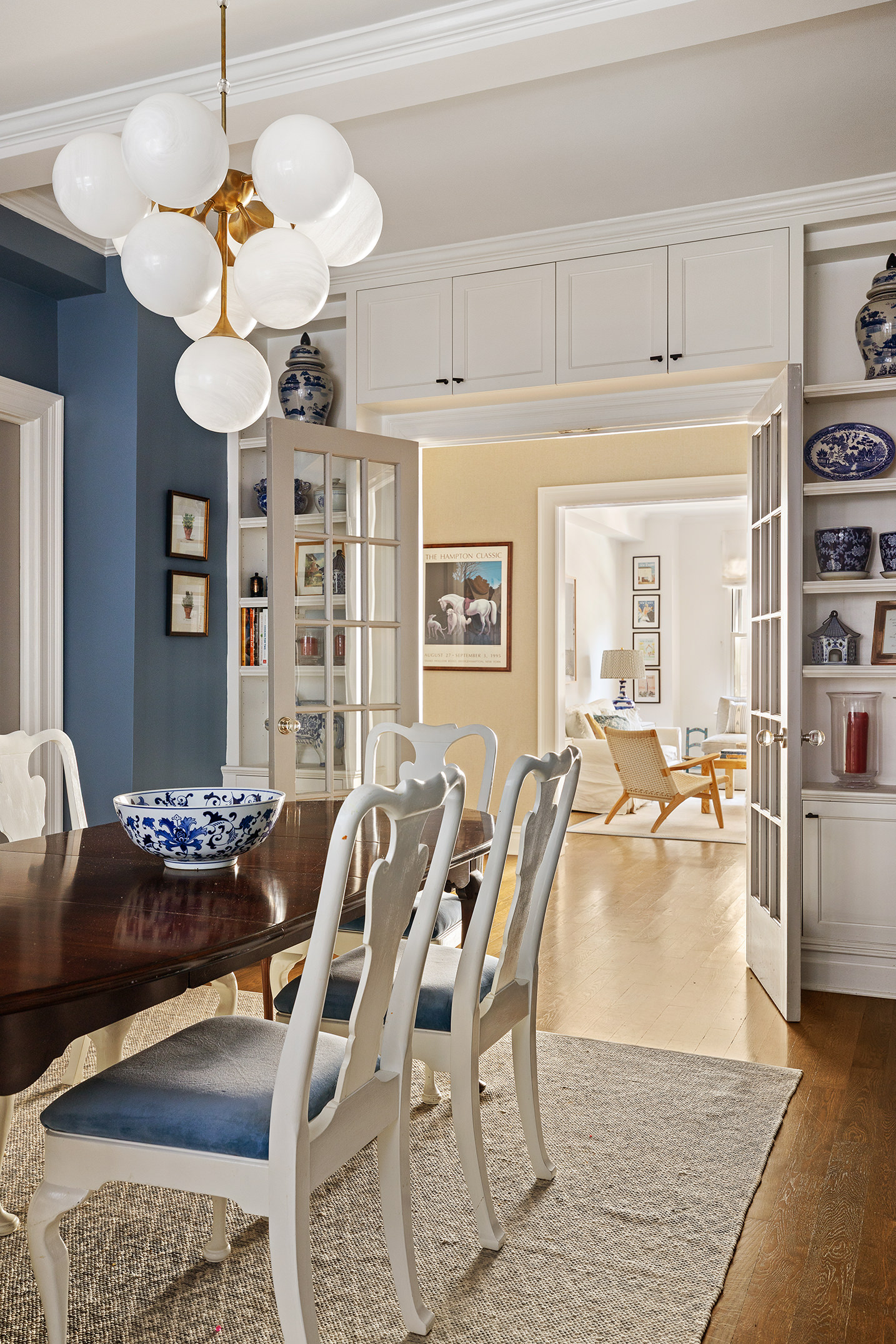 129 East 82nd Street, Unit 1C Manhattan, NY 10028 - Photo 3 of 13 a dining room with wooden floor a chandelier a wooden table and chairs