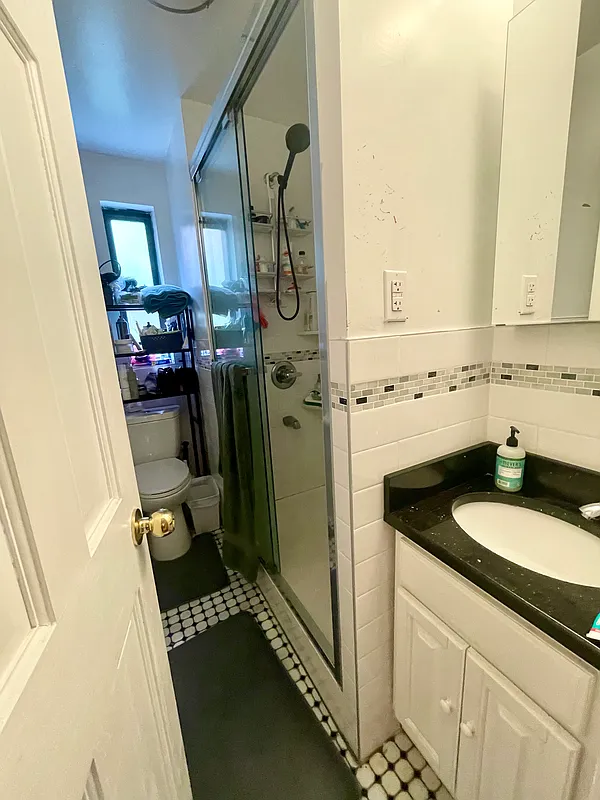 210 Thompson Street, Unit 4DN Manhattan, NY 10012 - Photo 9 of 10 a bathroom with a granite countertop sink and a mirror