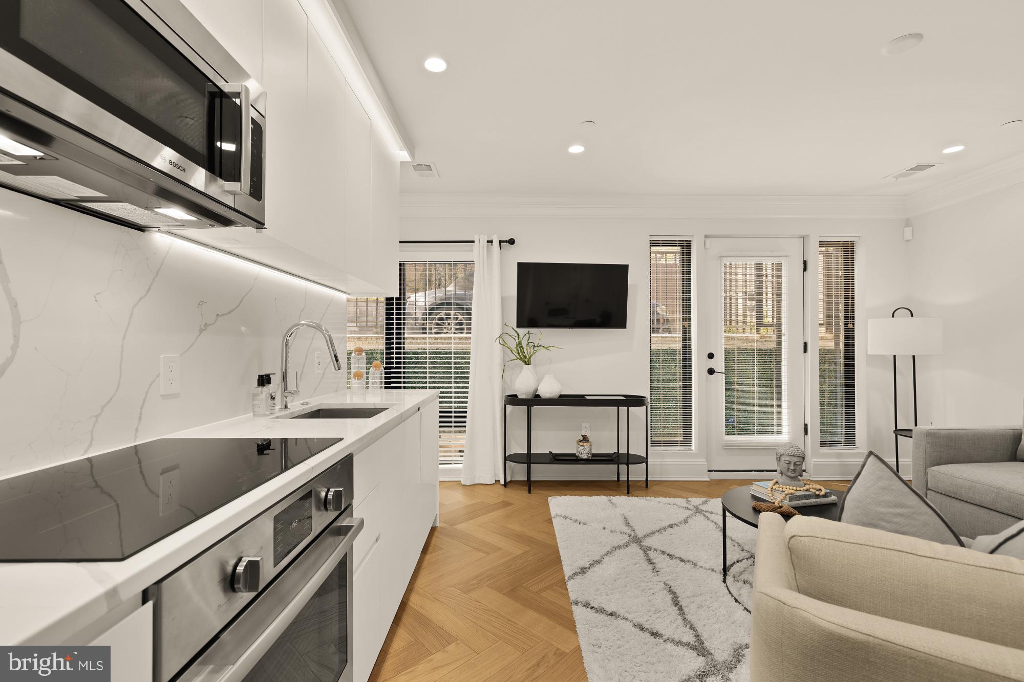 2630 39th Street Northwest, Unit 1 Washington, DC 20007 - Photo 13 of 26 a large kitchen with stainless steel appliances kitchen island granite countertop a sink and a stove top oven with wooden floor