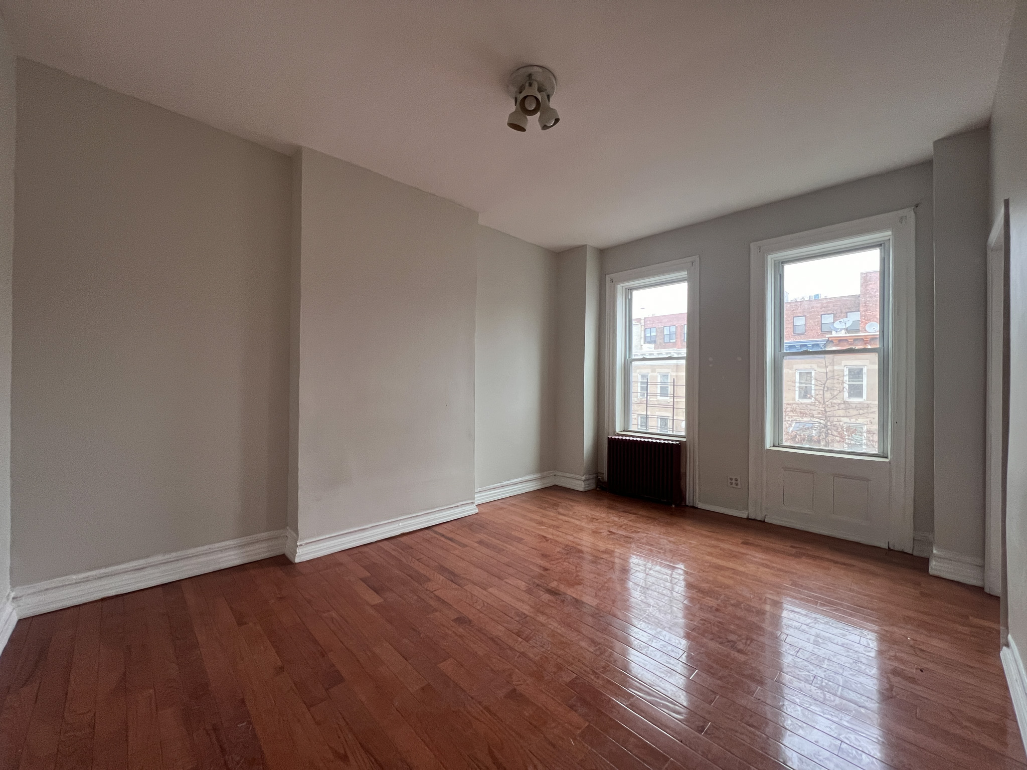 236 45th Street, Unit 2 Brooklyn, NY 11220 - Photo 5 of 8 an empty room with wooden floor and windows
