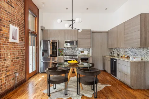 a kitchen with stainless steel appliances kitchen island granite countertop a table chairs in it and wooden floors
