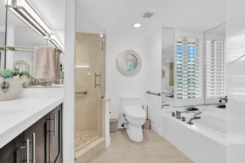 a bathroom with a bathtub a sink a toilet and a large mirror