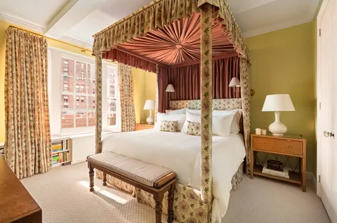 a bedroom with a bed next to a window and a chandelier