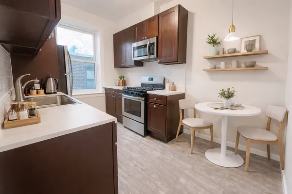 a kitchen with stainless steel appliances a sink a stove a microwave a dining table and chairs