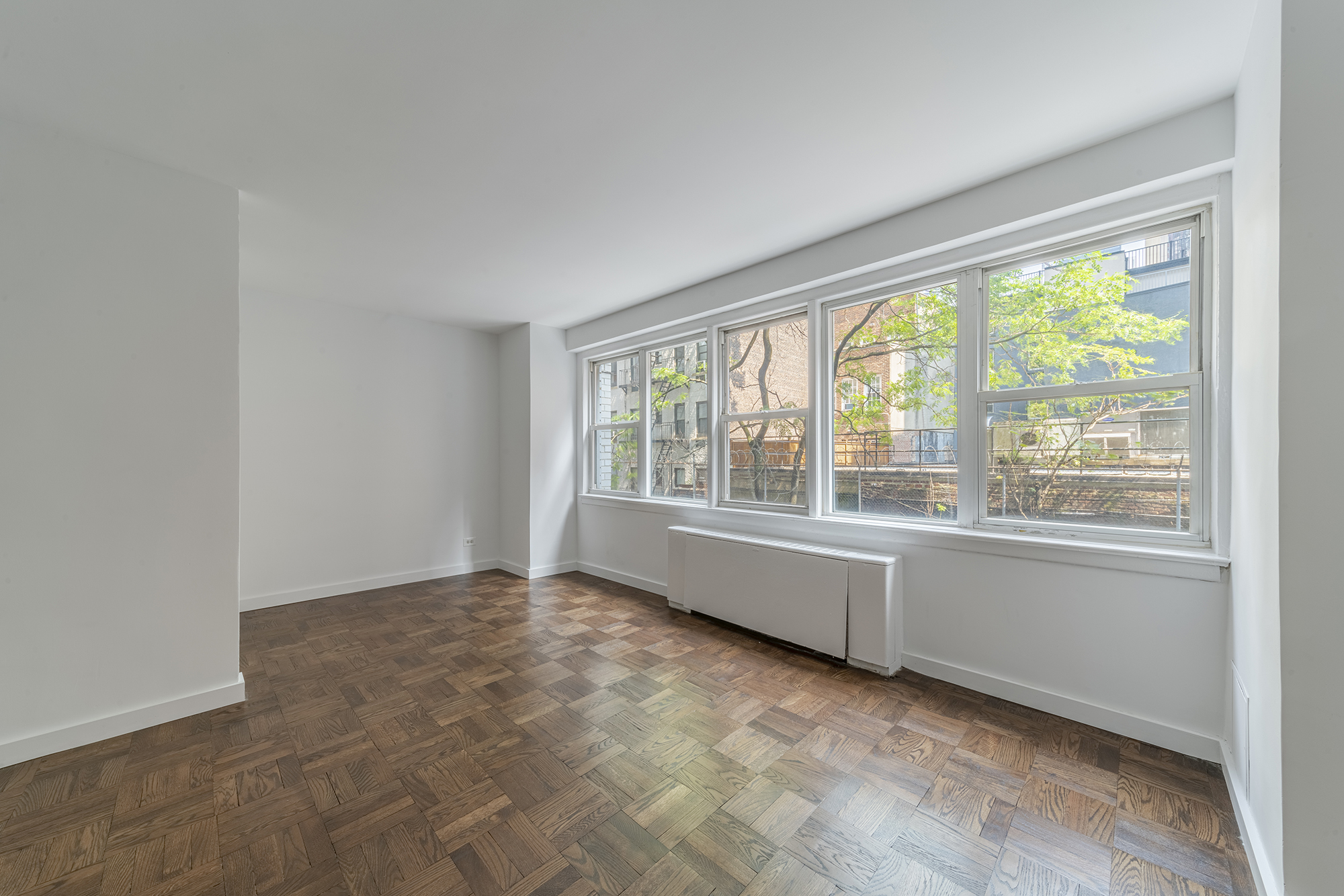 155 East 34th Street, Unit 3B Manhattan, NY 10016 - Photo 4 of 11 an empty room with wooden floor and windows