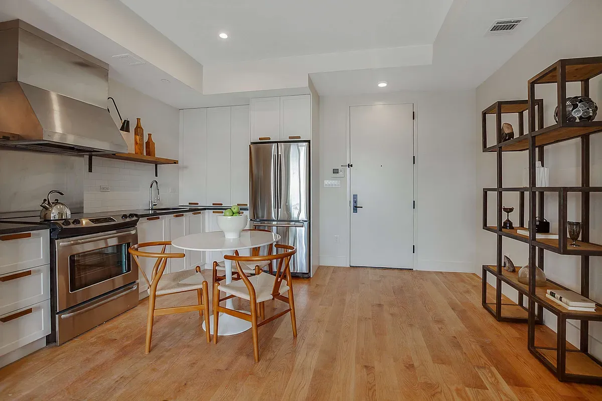 a kitchen with stainless steel appliances granite countertop a table chairs stove and cabinets