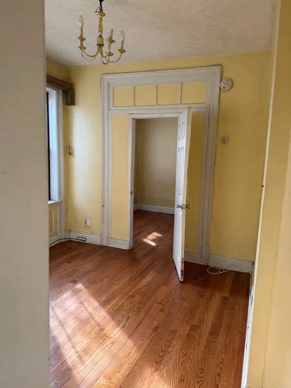 an empty room with wooden floor and mirror
