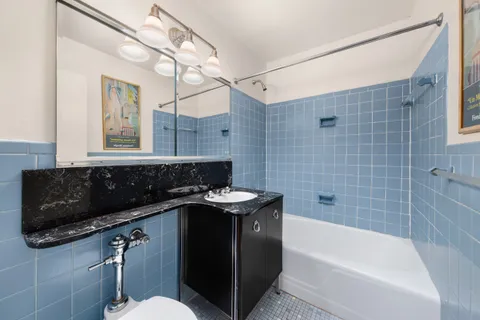 a bathroom with a granite countertop sink a toilet a mirror and bathtub