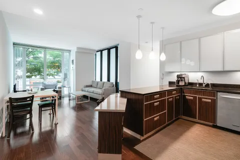 a kitchen with kitchen island granite countertop a stove a sink a dining table and chairs with wooden floor