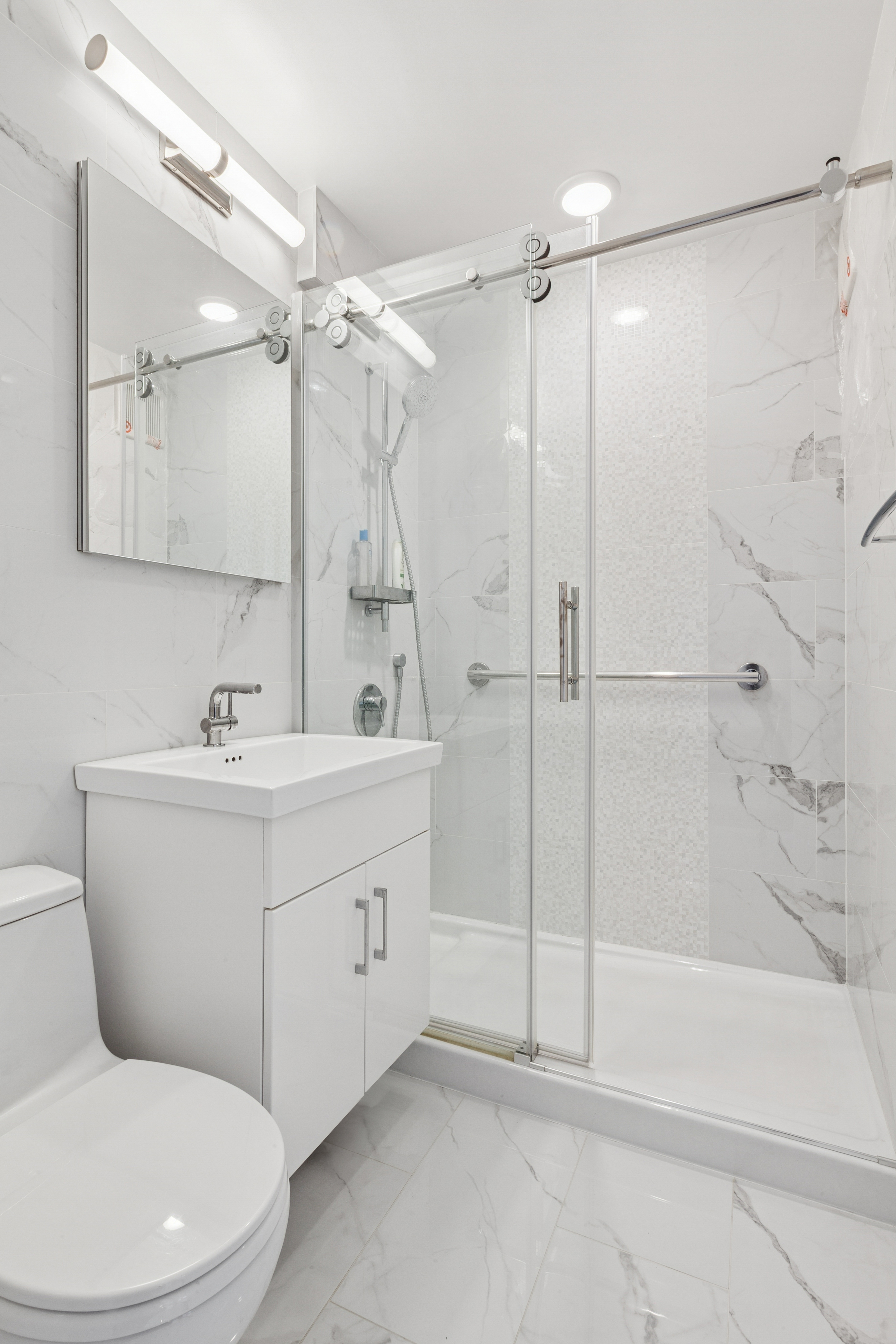 70-25 Yellowstone Boulevard, Unit 8N Queens, NY 11375 - Photo 7 of 19 a bathroom with a sink mirror and a shower
