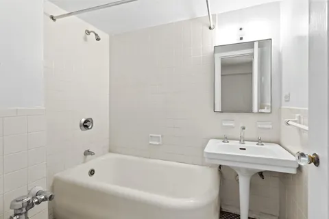 a bathroom with a tub sink and mirror
