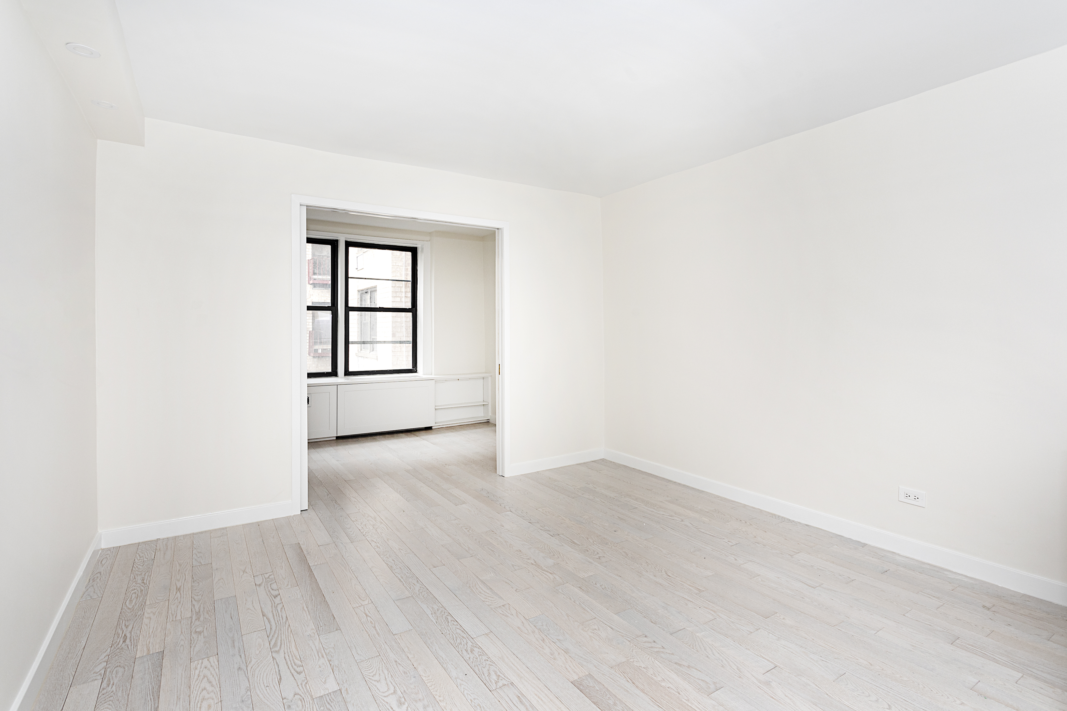 165 Christopher Street, Unit 1C Manhattan, NY 10014 - Photo 4 of 10 an empty room with wooden floor and windows