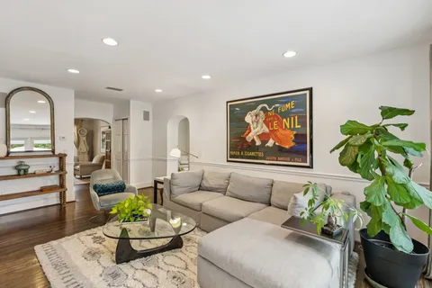 a living room with furniture potted plant and kitchen view