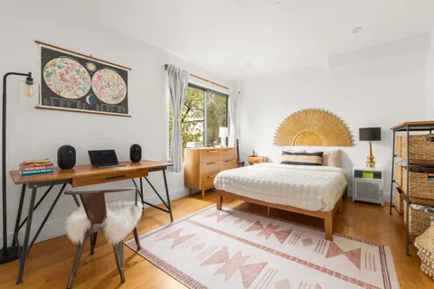 a bedroom with a bed a chair and a potted plant