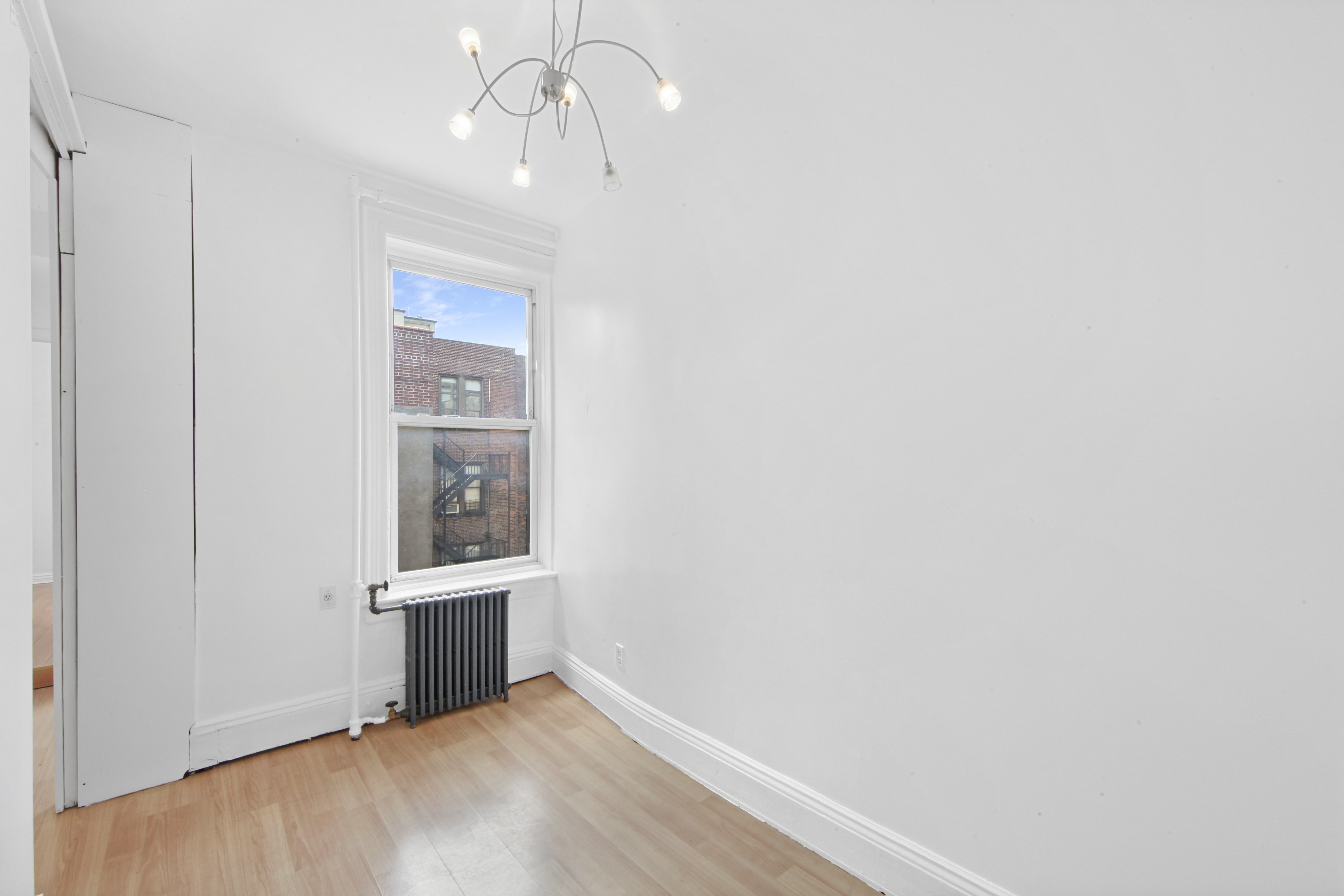150 Sullivan Street, Unit 37 Manhattan, NY 10012 - Photo 3 of 12 an empty room with wooden floor cabinet and windows