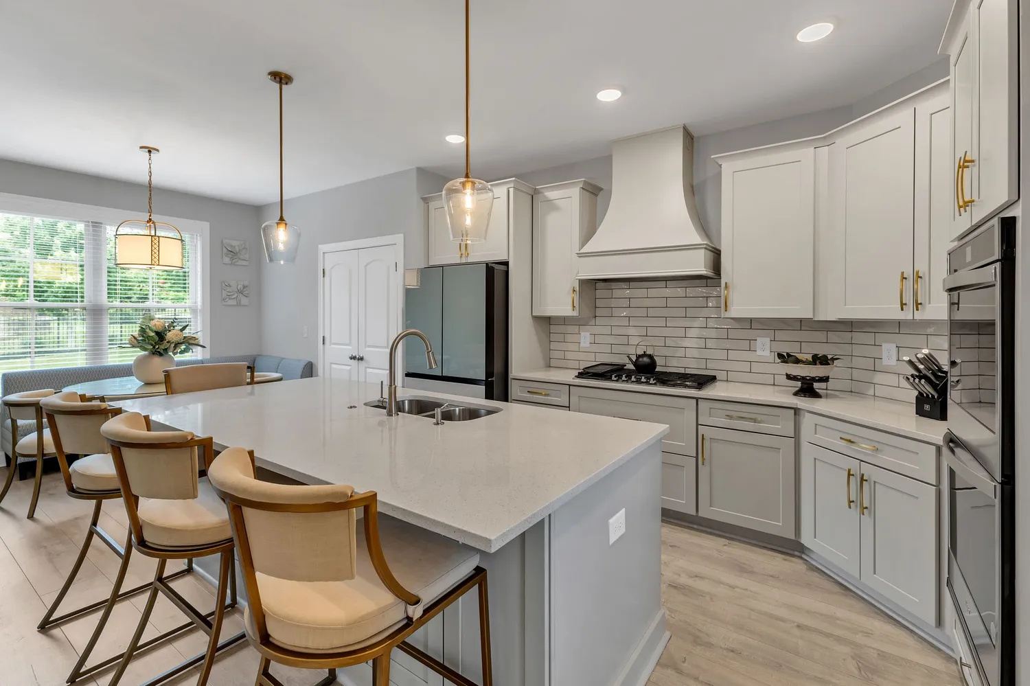 a kitchen with stainless steel appliances kitchen island granite countertop a sink a stove a refrigerator and white cabinets with wooden floor