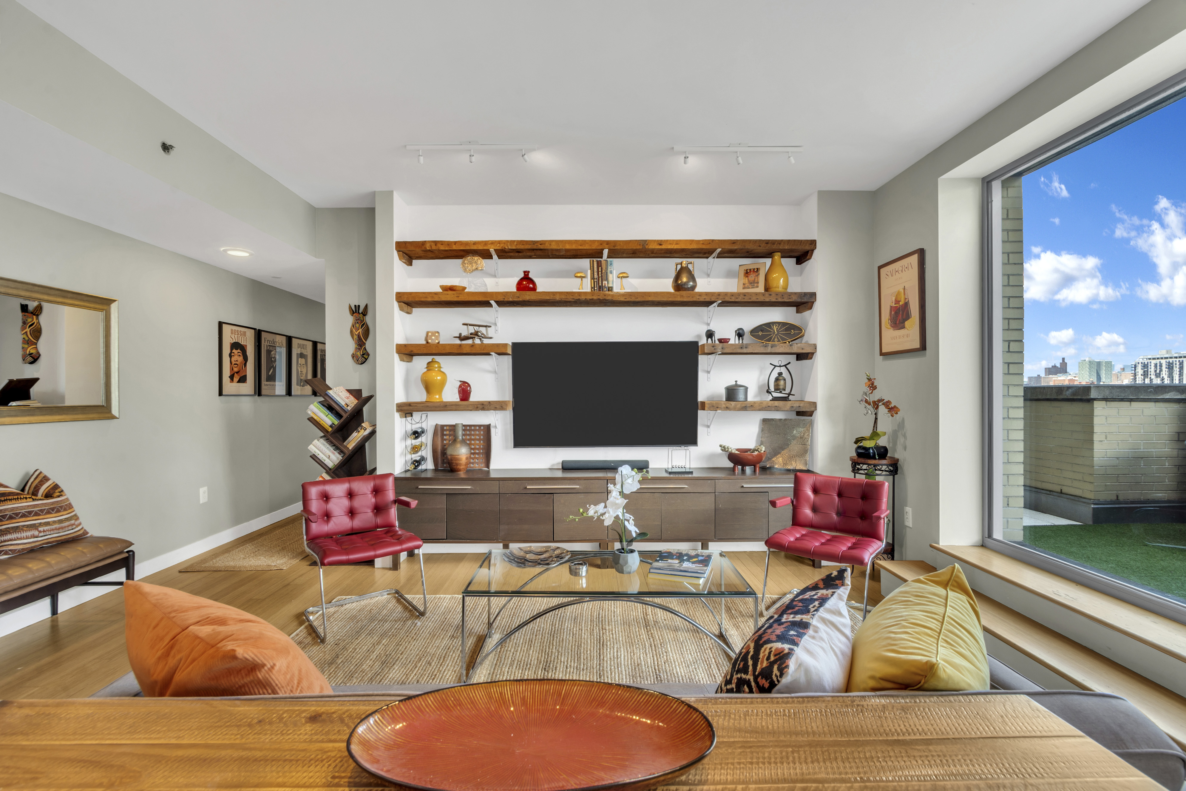 40 West 116th Street, Unit A907 Manhattan, NY 10026 - Photo 3 of 34 a living room with furniture a flat screen tv and a floor to ceiling window