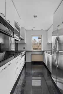 a kitchen with granite countertop a refrigerator and white cabinets