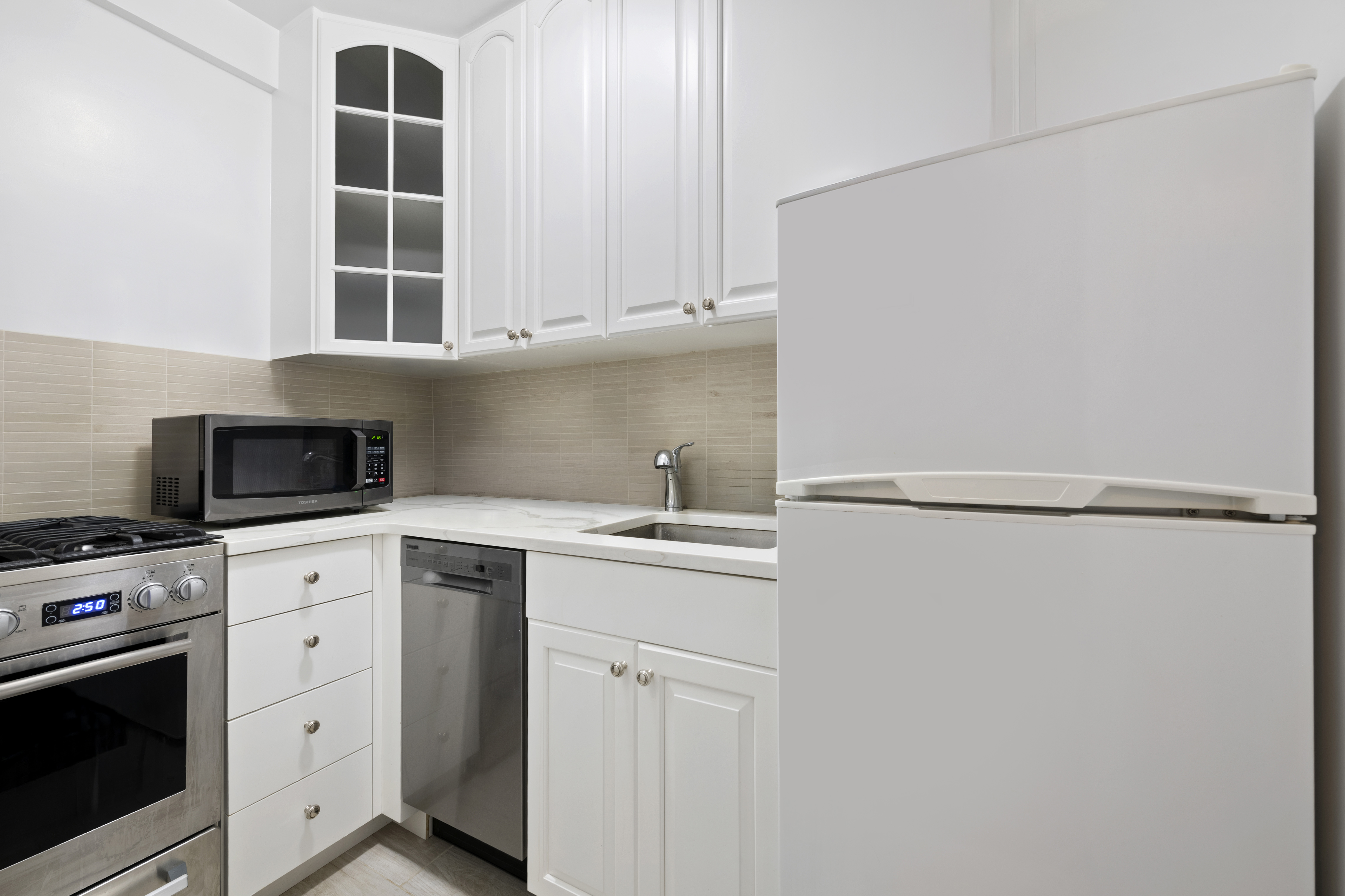 408 West 57th Street, Unit 3A Manhattan, NY 10019 - Photo 4 of 11 a kitchen with white cabinets and refrigerator
