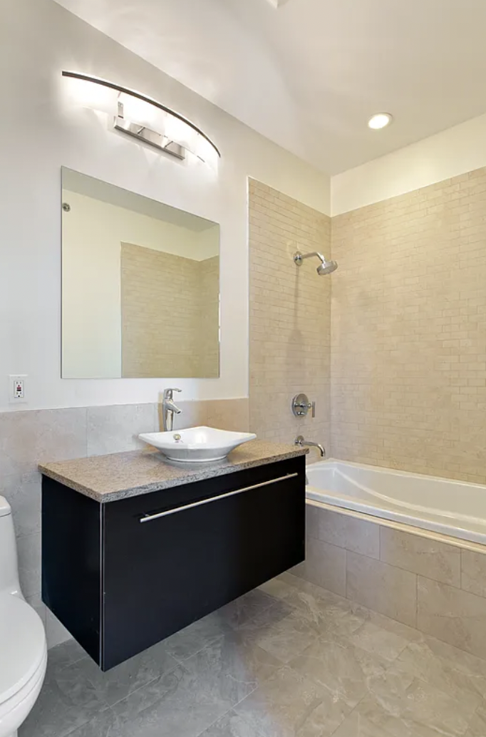 42-37 27th Street, Unit 8B Queens, NY 11101 - Photo 4 of 11 a bathroom with a double vanity sink toilet mirror and bathtub