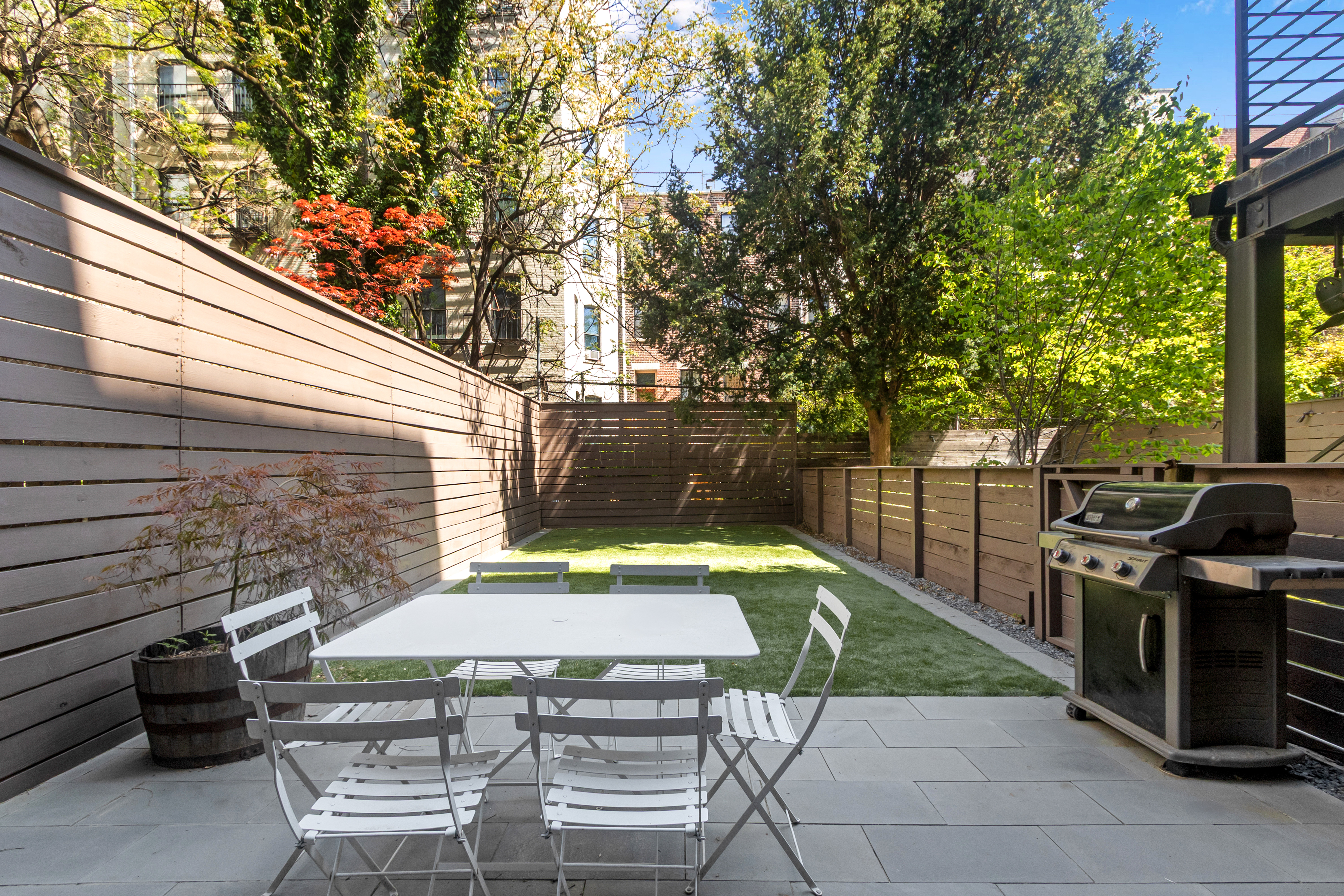 125 West 132nd Street Manhattan, NY 10027 - Photo 3 of 21 a view of a patio with a table and chairs under an umbrella with large trees