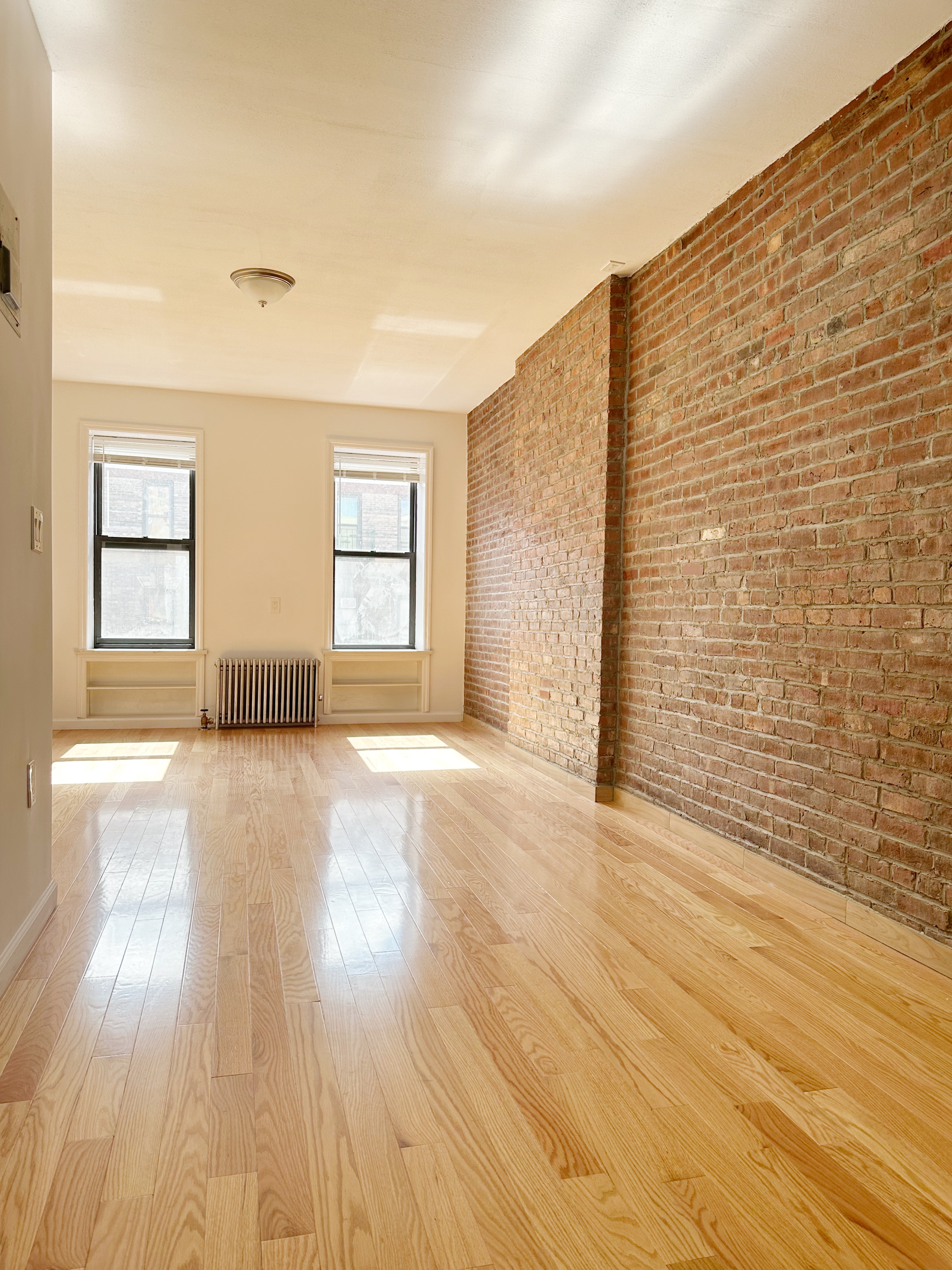 75 Madison Street, Unit 9 Manhattan, NY 10002 - Photo 4 of 6 a view of an empty room with wooden floor and a window