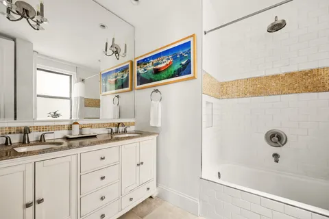 a bathroom with a granite countertop sink a mirror a bathtub and shower