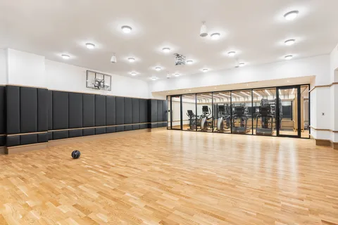 a view of an empty room with wooden floor and fence