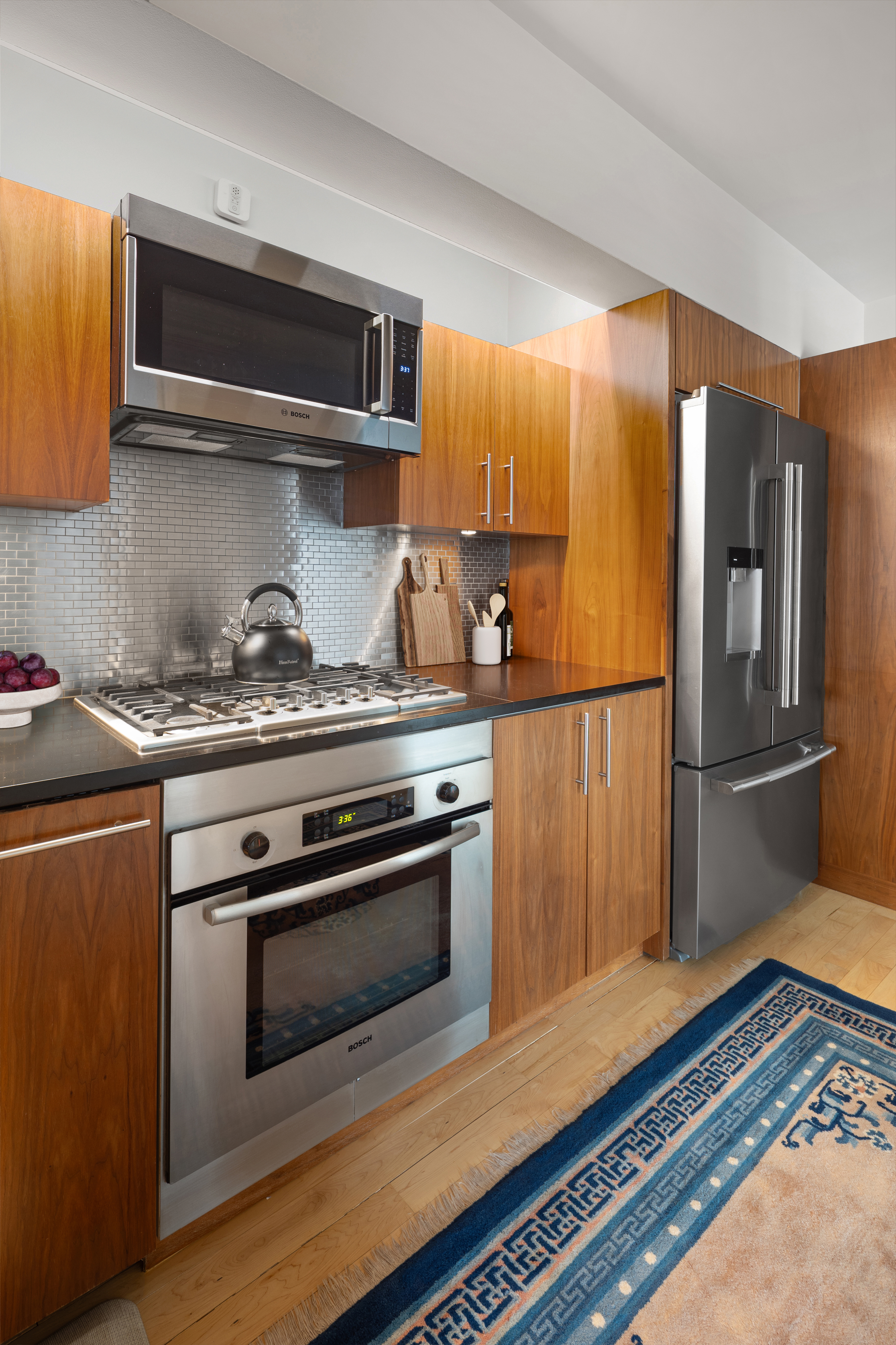 15 Broad Street, Unit 1900 Manhattan, NY 10005 - Photo 8 of 29 a kitchen with stainless steel appliances and wooden cabinets