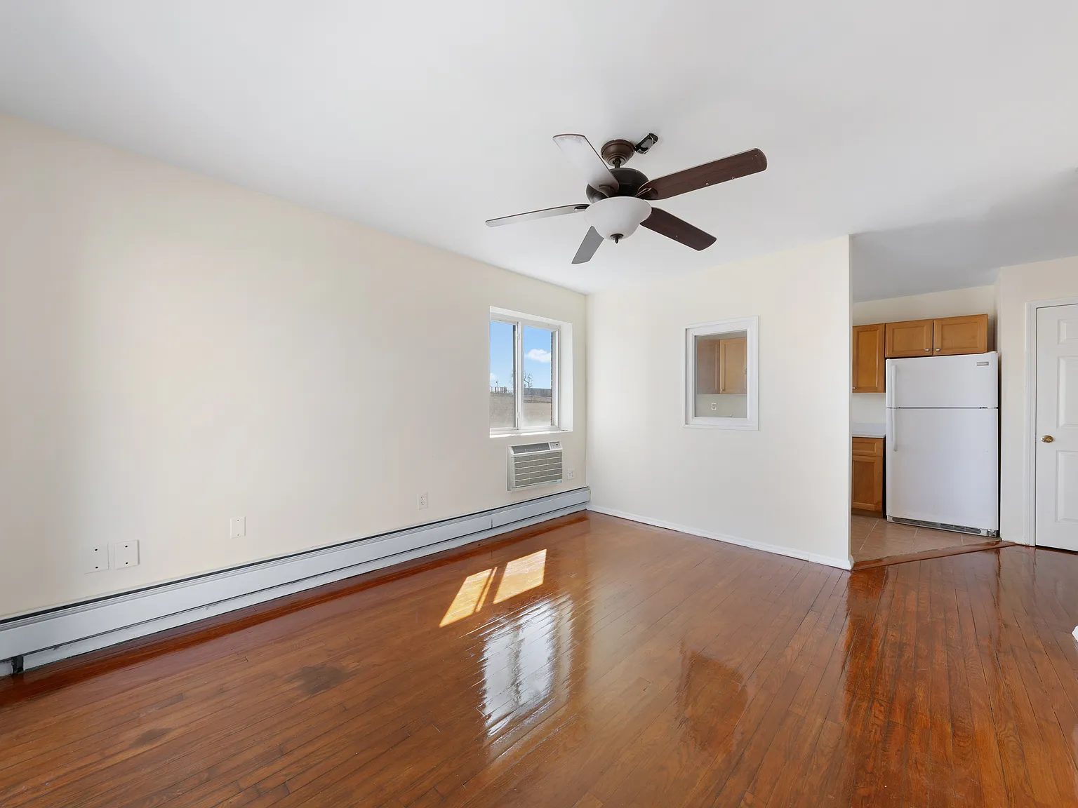 a view of empty room with wooden floor and fan
