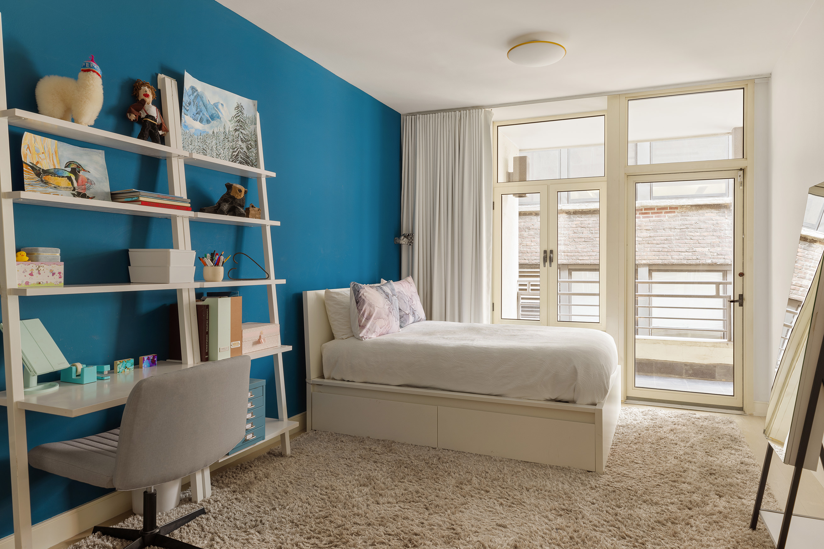 129 West 20th Street, Unit 4B Manhattan, NY 10011 - Photo 12 of 16 a bedroom with a bed a book shelf and a window