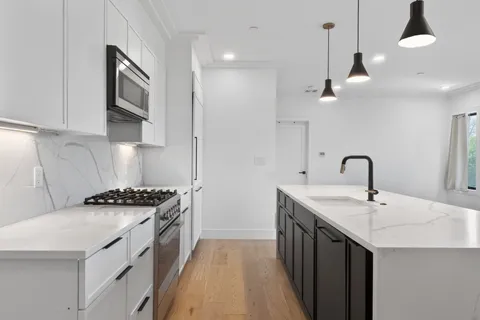a kitchen with stainless steel appliances a sink a stove and a wooden floors