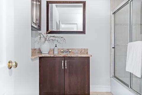 a bathroom with a granite countertop sink a mirror and a shower