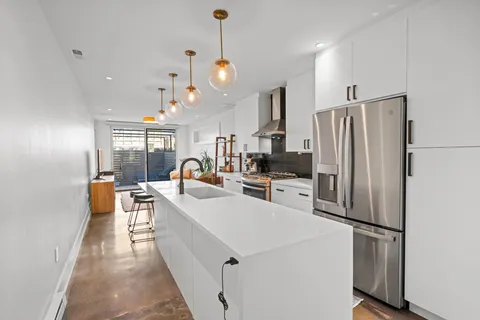 a kitchen with stainless steel appliances a refrigerator a stove a sink dishwasher a oven and a dining table with wooden floor